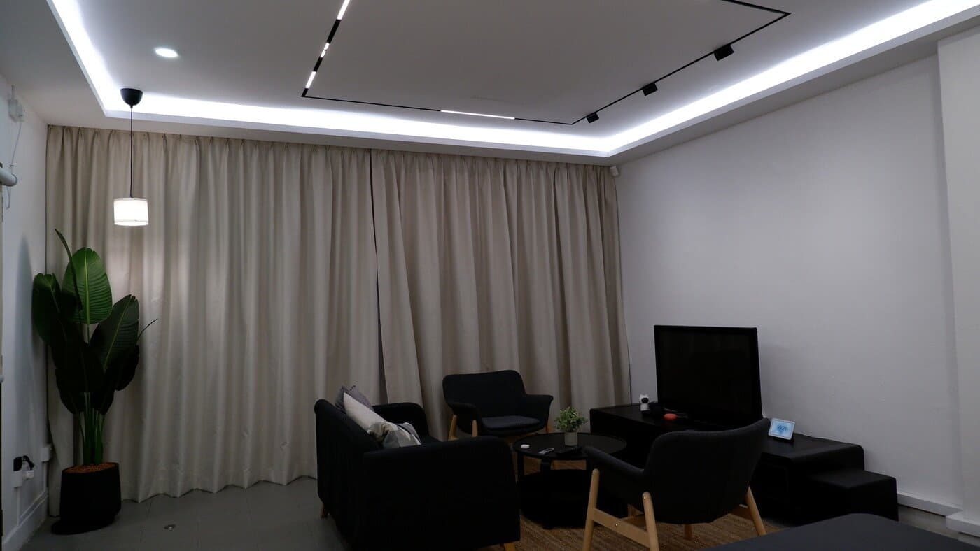 LED strip cove lighting and magnetic track lights around a living room false ceiling